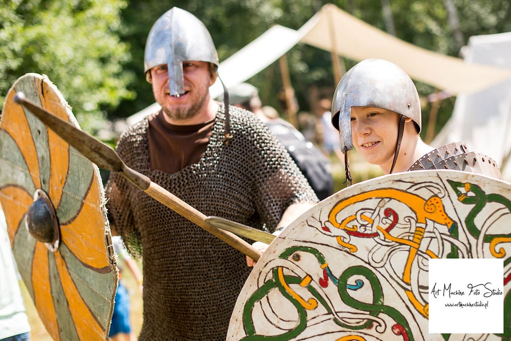 Ojciec z synem bawiący się podczas pikniku historycznego przebrani w elementy uzbrojenia średniowiecznego.