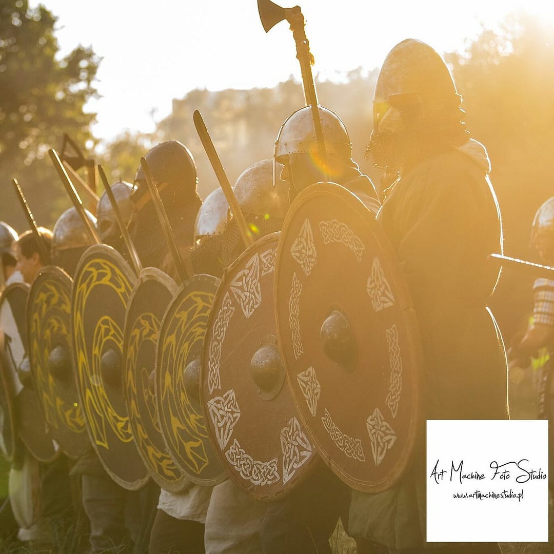 Wojowie średniowieczni stojący w linii na tle zachodzącego słońca.