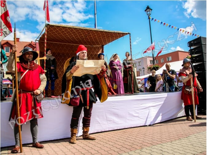 Herold odczytujący prawa miejskie przed dworem króla, z tłumem słuchających dworzan i rycerzy.